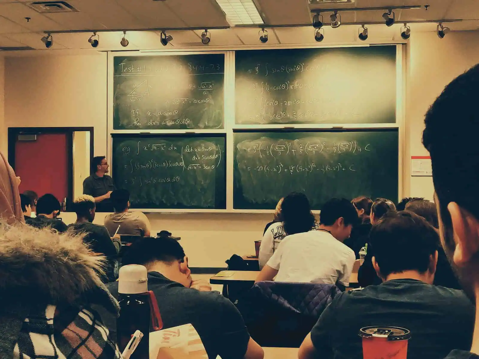 college student sitting on chairs in front of chalkboard