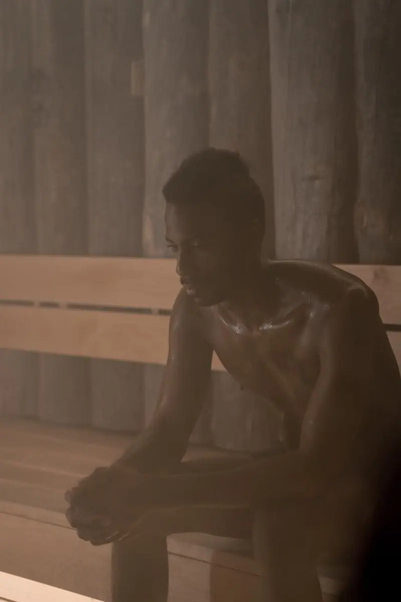 A Shirtless Man Sitting Inside the Sauna