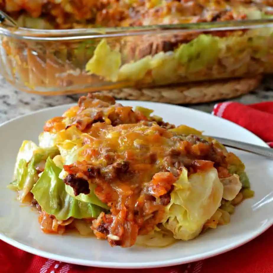 a serving of cabbage roll casserole on a white plate with the casserole dish in the background