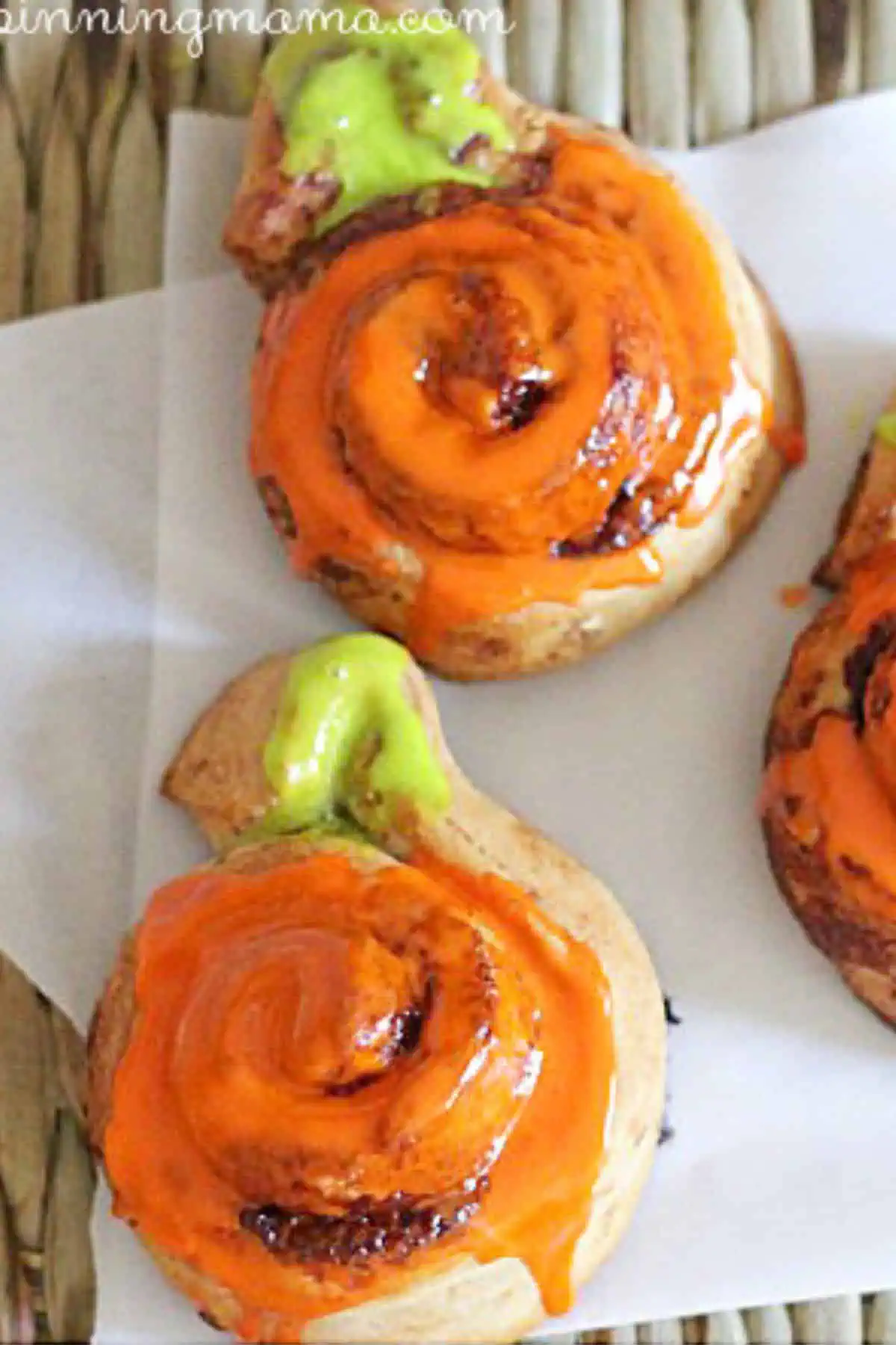 Cinnamon rolls in the shape of pumpkins with orange and green icing