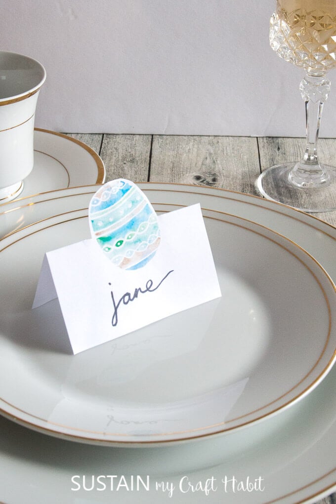 Free printable egg place card settng on white and gold plate.