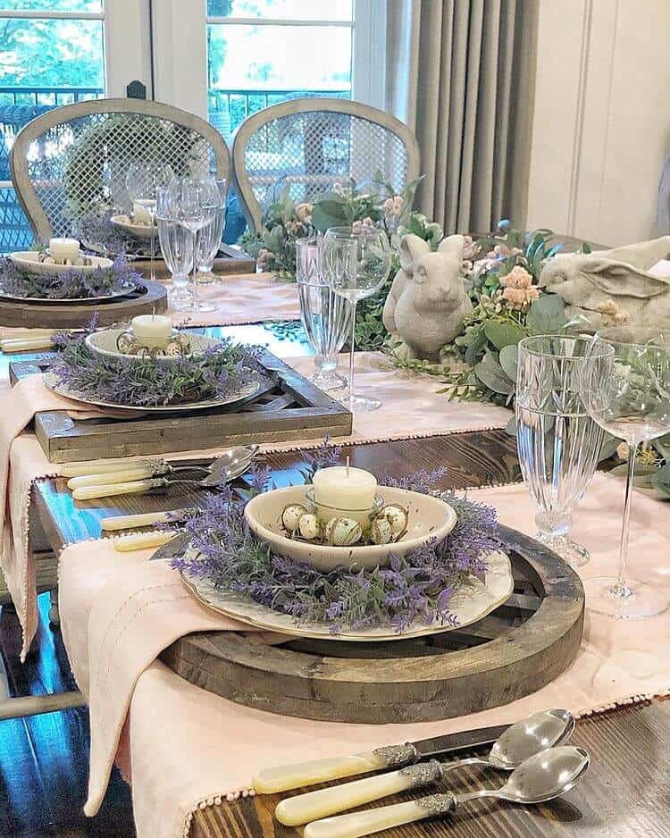 Farmhouse style Easter Tablescape idea with natural wood chargers, lavendar wreaths on white plates and a candle set at each place setting.