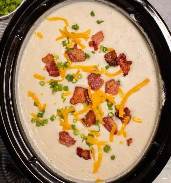 Loaded crockpot potato soup with bacon and cheese on top in a slow cooker