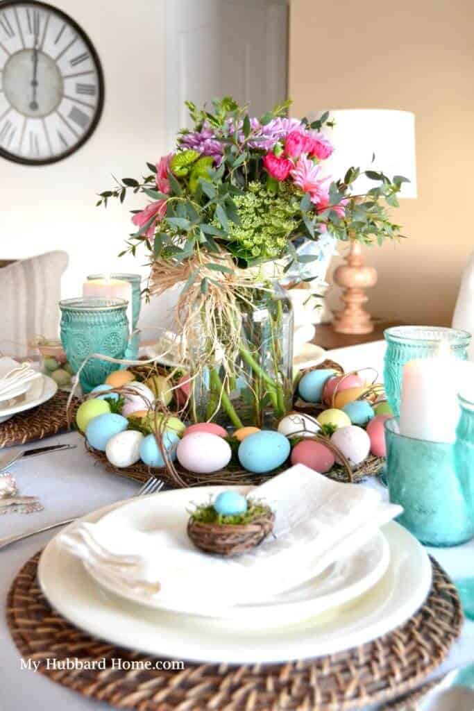 Egg wreath centerpiece with fresh flowers in a mason jar. Natural ratan charger with white plates and a small birds nest at each place setting.