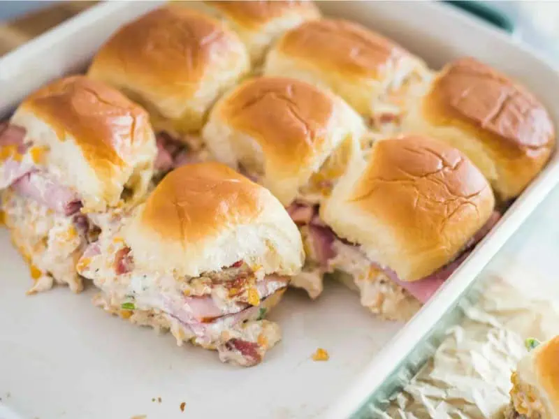 image 18989 - The only sin in Mississippi Sin Sliders is how sinfully good they taste! Mississippi Sin is actually a creamy, cheesy, and savory dip infused with bacon bits—a dip that's lovingly spread on both sides of the buttery rolls in each slider. With a few slices of warmed ham for extra meatiness, Mississippi Sin Sliders are more than welcome at tailgating parties, barbeques, and any other sunny get-together. They're perfect for tearing, sharing, and slicing up, and you can have them ready for the party in just an hour! You may want to make two batches because these go fast!