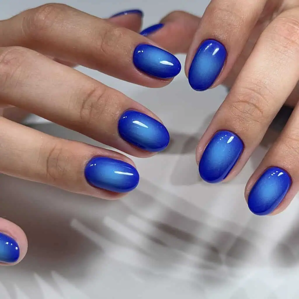 Varied blue nail designs showcasing light blue nails, royal blue acrylic nails, and blue French tips in different hand poses.