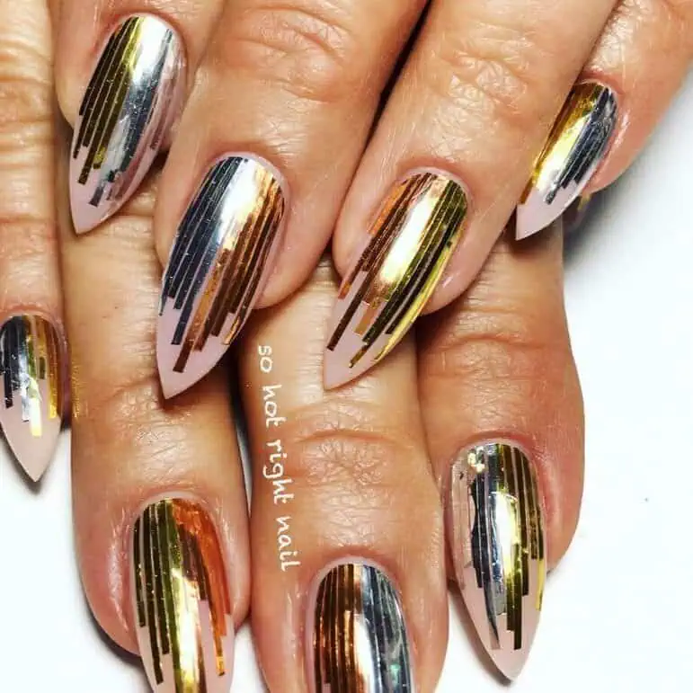 Hands displaying different metallic nail styles, featuring black nails with silver specks, dark gold polish, and shiny red acrylic nails.