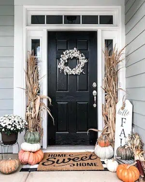 pumpkins and dried corn stalks on either side of the door